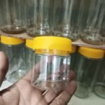 Two transparent PET plastic jars with bright yellow screw caps displayed on a clean white background. One tall 230ml jar and one shorter 130ml jar are shown with black arrows and text indicating their height and base dimensions.