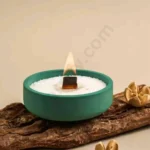 An extremely low-profile, wide round clear glass candle jar in Nordic style on a wooden table.