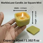 A hand holding a small, light olive green and multiple color square candle jar with rounded corners made of solid marble powder, shown with a matching square lid and a lit candle flame graphic. jarsify