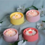 MarbleLuxe ribbed candle jars in blue, yellow, and white, made from solid marble powder, shown with lit candle flames on a split white and wood background. jarsify